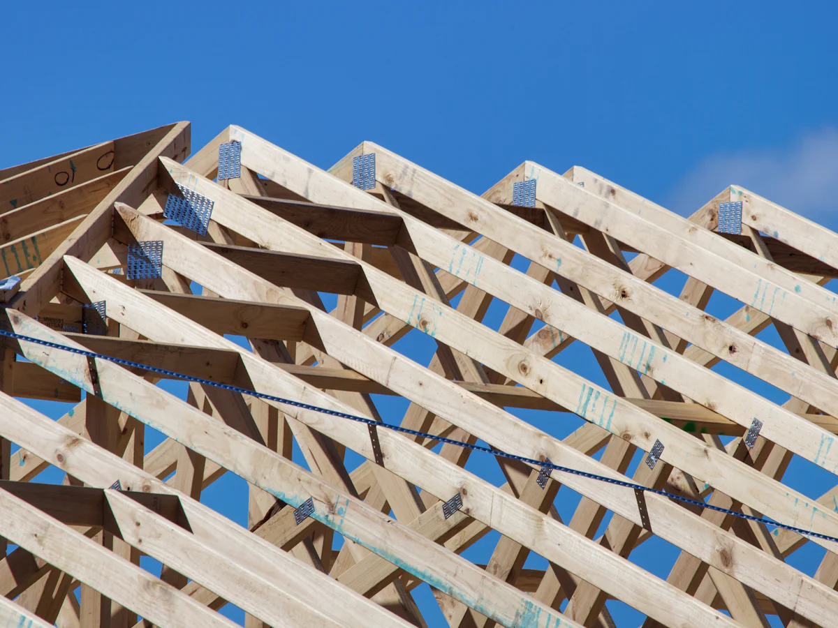 Wooden roof trusses against a blue sky